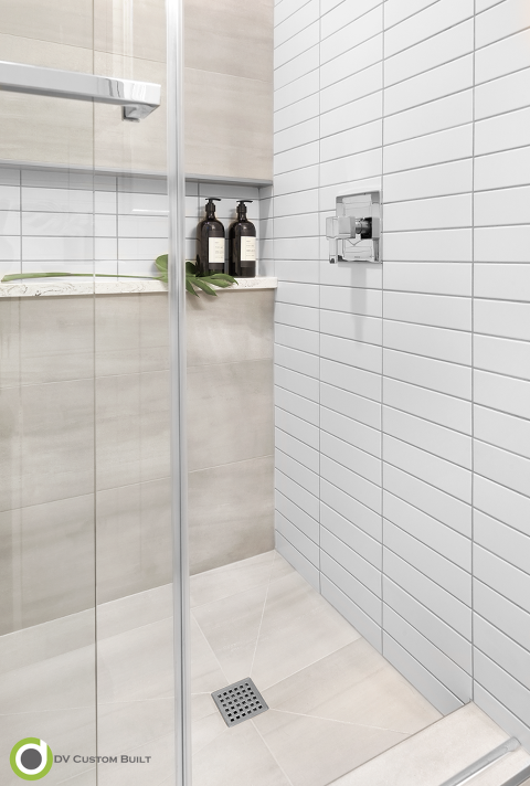 photo of glass shower with white subway tile, shelf cut out with quartz ledge and tiled shower pan to match